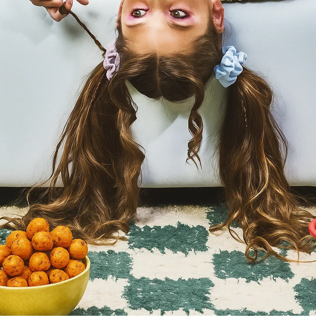 Child with pigtails lying on a couch with makhana bowl around